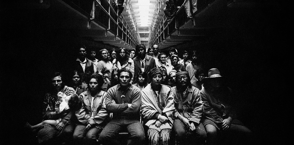 an image of a group of people seated with their arms crossed, two rows deep, looking at the camera