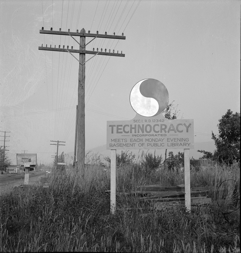 A road sign stands in tall weedy grass with a telephone poll overhead. The sign is centered with a large yin yang emblem reads "Technocracy Incorporated. Meets Each Monday Evening Basement of Public Library".
