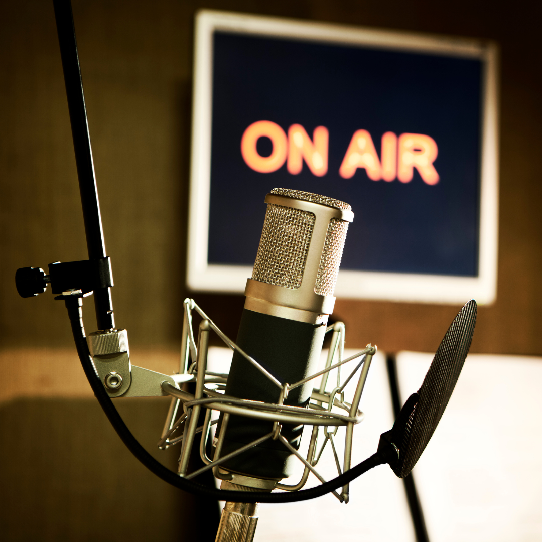 a podcast microphone with the "on air" sign flashing in the background