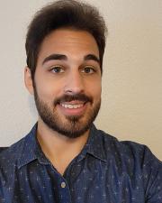 Man with a beard in a blue collared shirt smiling at the camera
