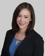 A woman with shoulder length hair wearing a black blazer while smiling at the camera.