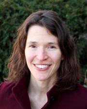 A woman with brown hair and a Burgundy collared shirt smiling at the camera