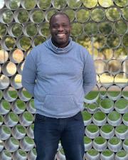 a man wearing a grey hoodie smiling at the camera