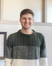 A man wearing a green and white sweater smiling at the camera