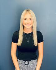 a woman with blond hair posing with her hands held in front of her, smiling at the camera