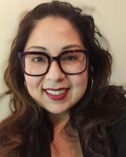 A woman with glasses smiling at the camera. 