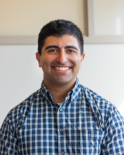 A man in a collared shirt smiling at the camera