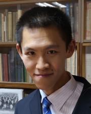 a man in a collared shirt and tie smiling at the camera