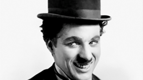 Black and white image depicting Charlie Chapman smiling away from the camera with a top hat on
