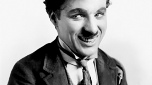 Black and white image depicting Charlie Chapman smiling away from the camera with a top hat on